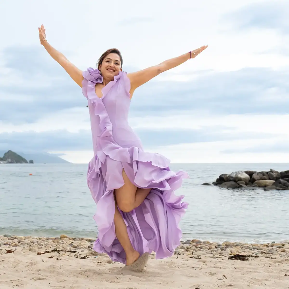 Woman in a lilac dress jumping with open arms on a Puerto Vallarta beach