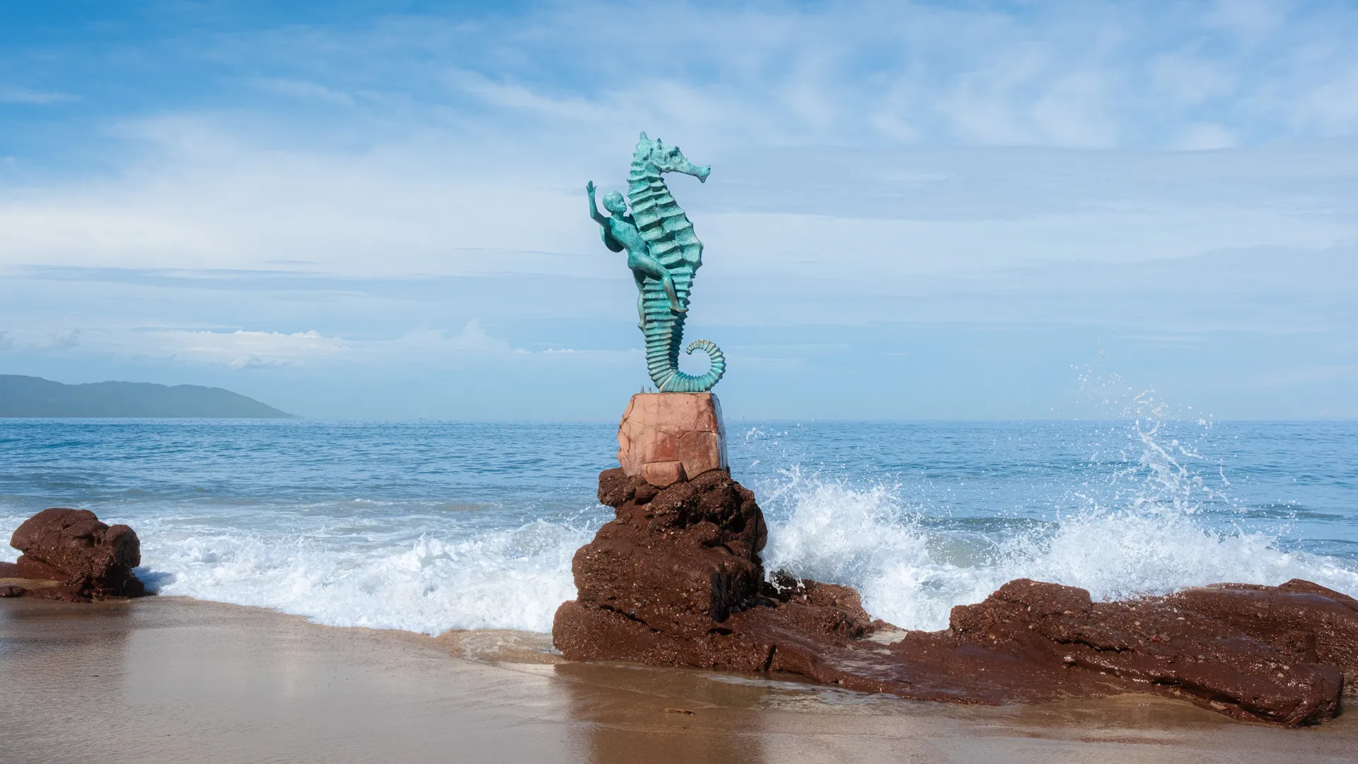 The original Boy on the Seahorse sculpture near Playa Amapas in Puerto Vallarta, with waves breaking against the rocks at its base