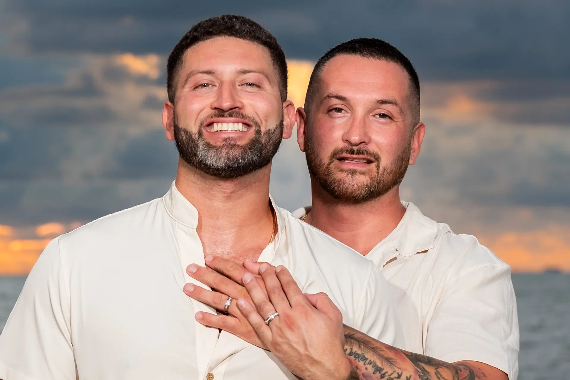 Same-sex male couple in a close portrait showing their wedding rings at sunset in Puerto Vallarta