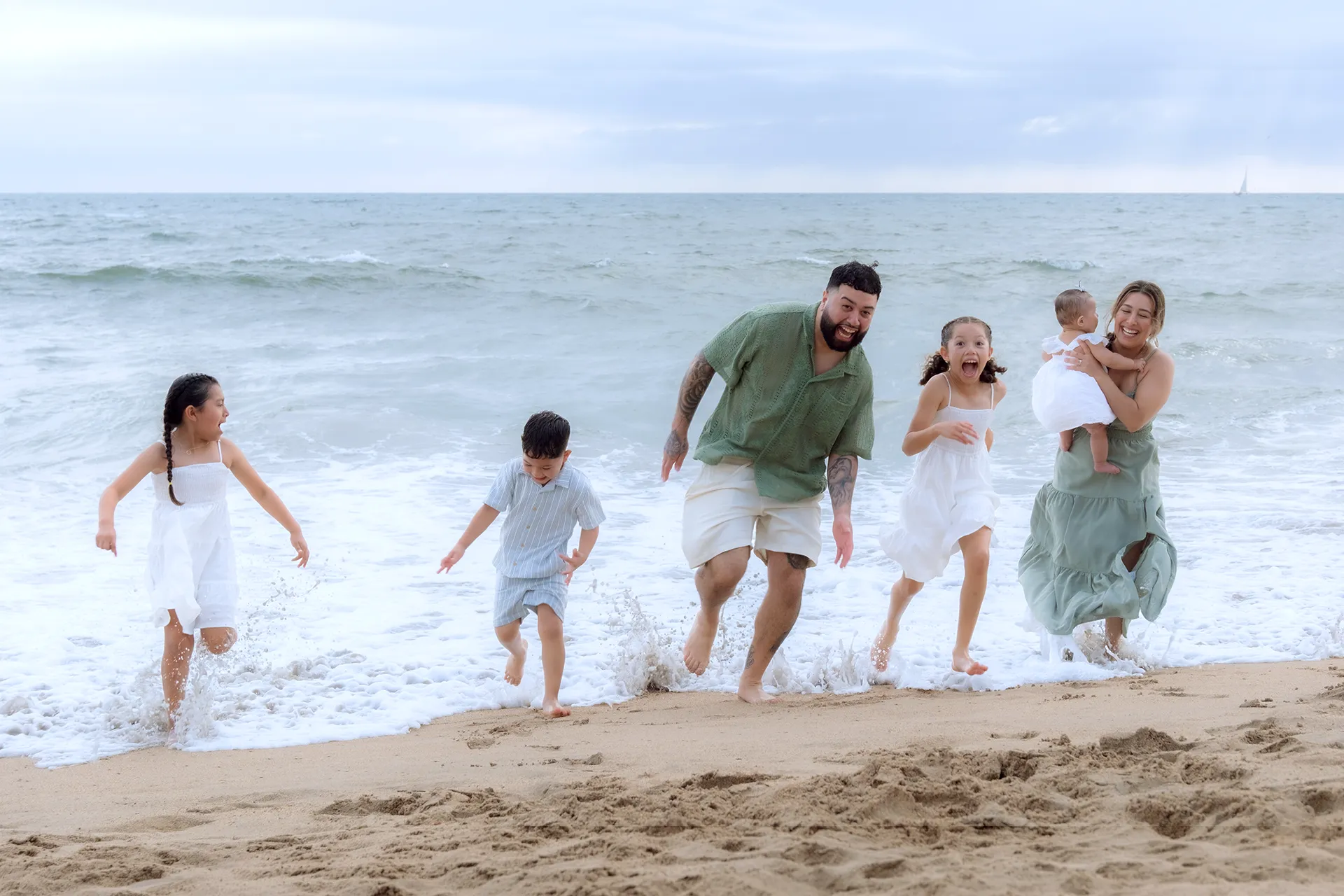 Father running out of the surf with his children during a family beach session in Puerto Vallarta