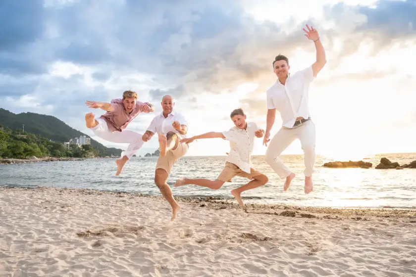 Family jumping together on the sand during a beach session in Puerto Vallarta