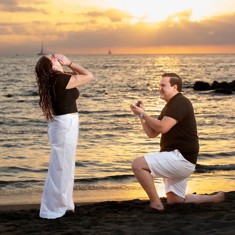 Man on one knee proposing to his partner on a Puerto Vallarta beach at sunset