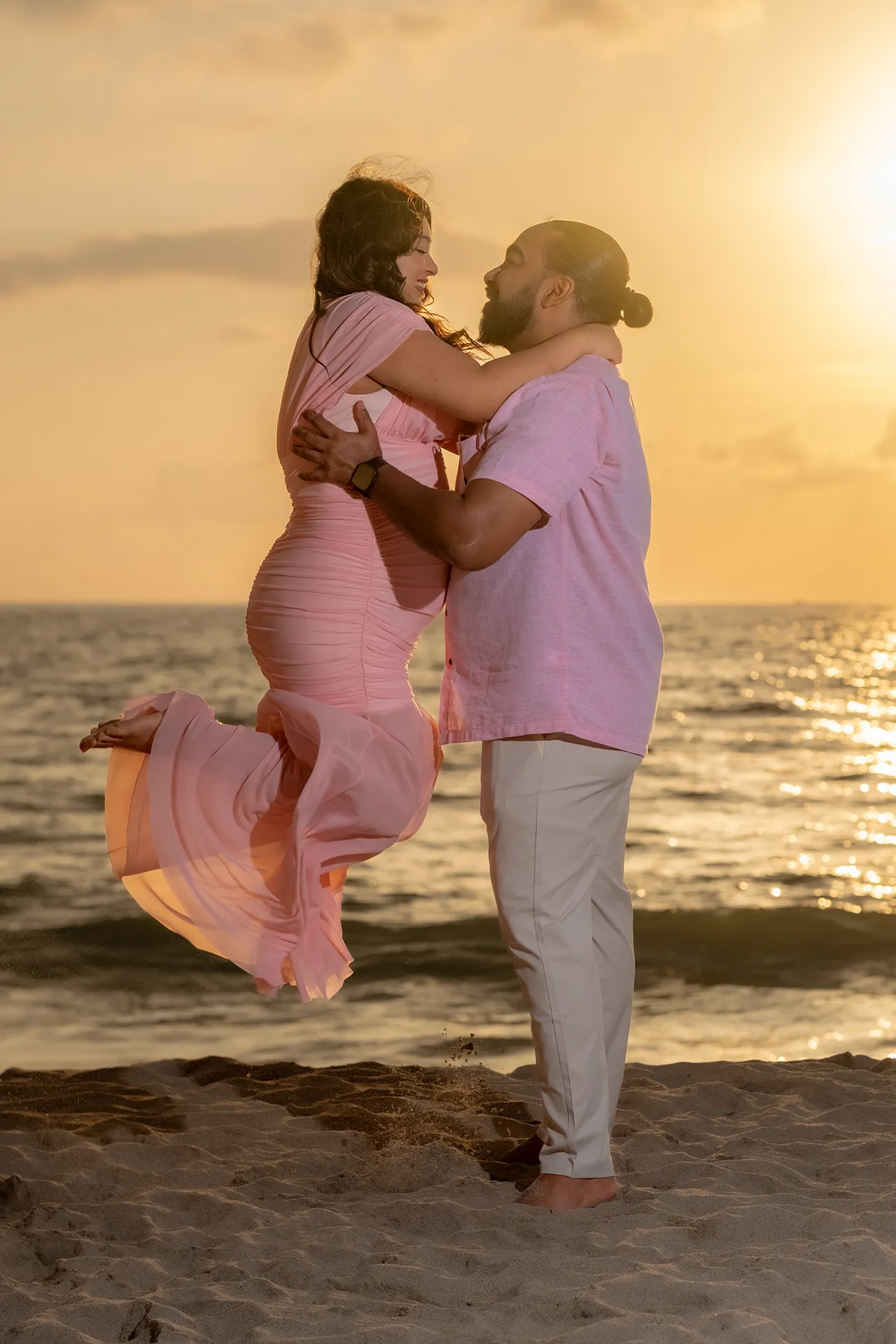 Expecting couple embracing and laughing at sunset during a maternity session in Puerto Vallarta