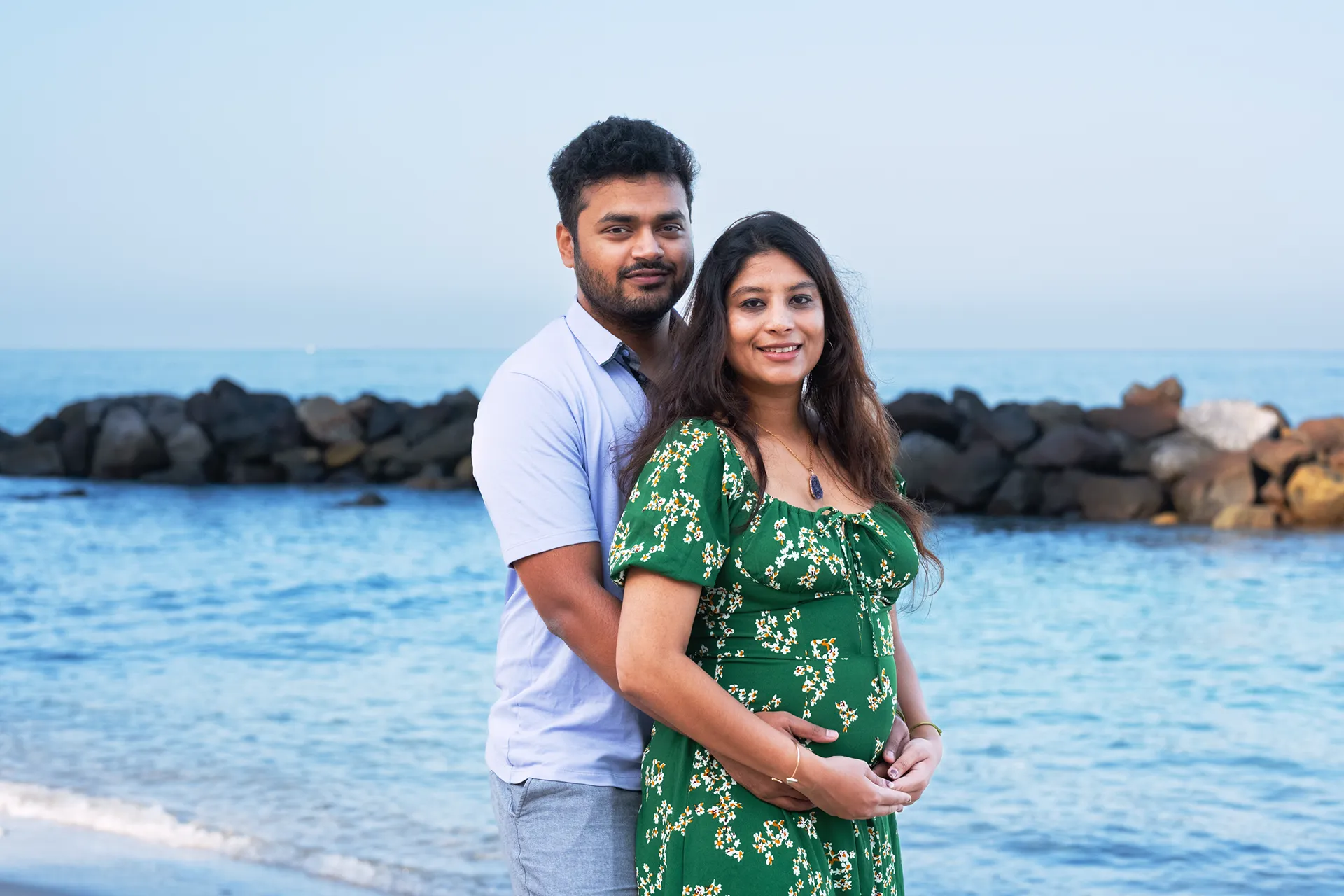 Expecting couple photographed by the rocks on a bright morning in Puerto Vallarta